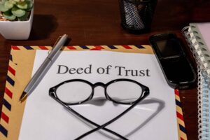 Deed of Trust document on desk with glasses, pen, and envelope.