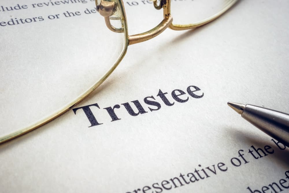 Photo of the word trustee written in white paper