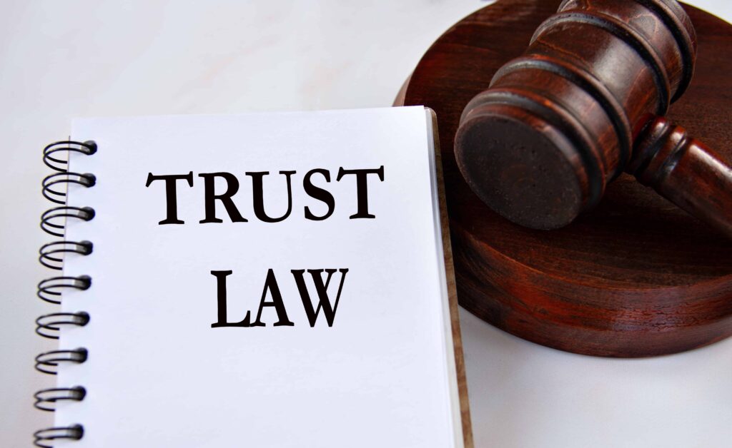 Trust law notebook and wooden judge’s gavel symbolizing legal regulations on trusts and estate planning.