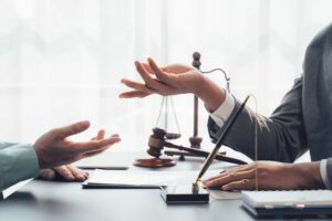 Lawyer consulting with client in office with legal documents, gavel, and justice scales on the desk.